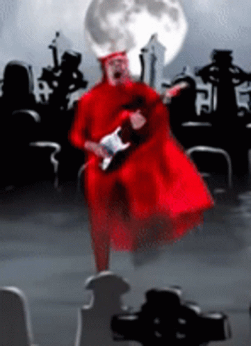 Man in Red Robe Playing Guitar in Cemetery With Full Moon
