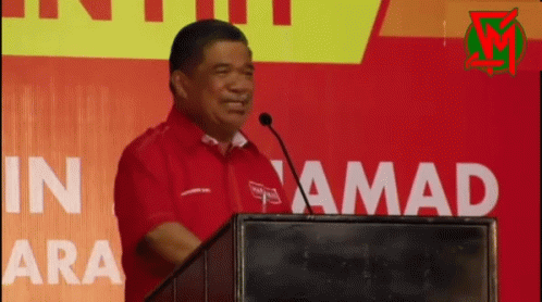 Man in Red Shirt at Podium With Microphone
