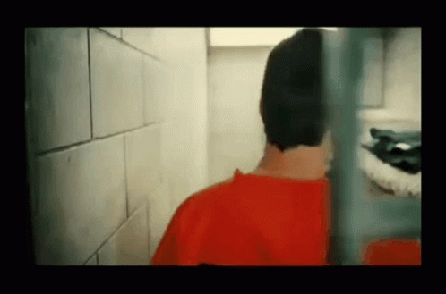 Man in Red Shirt Behind Prison Cell Fence