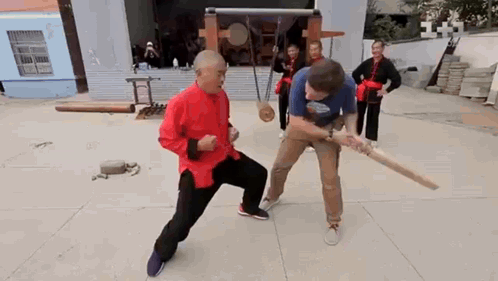 Man in Red Shirt Fighting With Wooden Bat