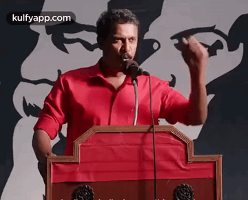 Man In Red Shirt Giving Speech At Podium With Microphone GIF