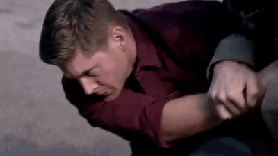 Man In Red Shirt Holding Another Man's Arm On Ground GIF