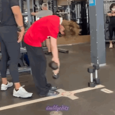 Man in Red Shirt Lifting Dumbbell While Another Man Watches