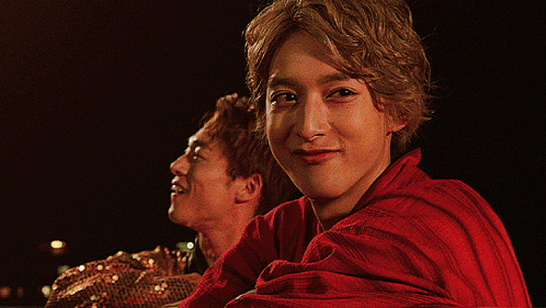 Man In Red Shirt Looking At Camera With Another Man Behind GIF