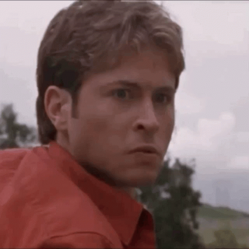 Man in Red Shirt Looking at Camera with Trees