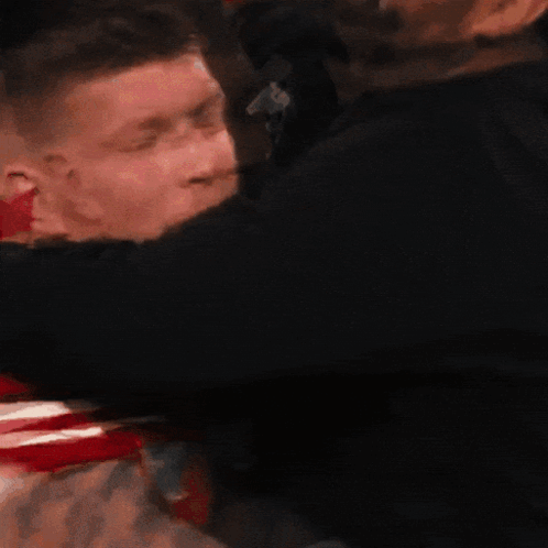 Man in Red Shirt Number 3 Hugged by Another Man