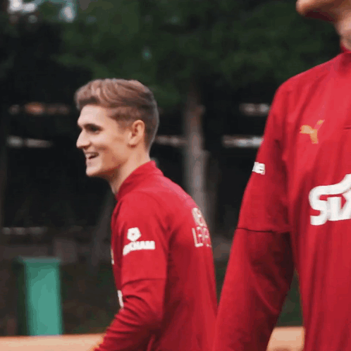Man In Red Shirt Smiling With Dam On Sleeve GIF