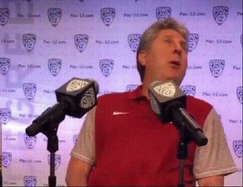 Man in Red Shirt Speaking Into Microphones