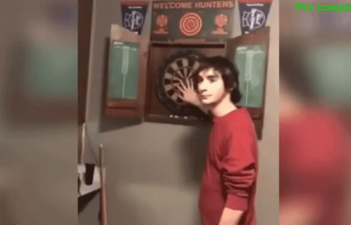 Man in Red Shirt Standing Before Dart Board