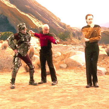 Man in Red Shirt Standing Next to Two Men in Black Pants