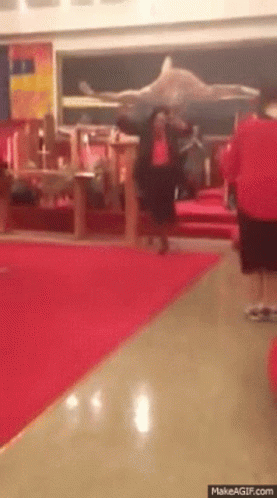Man in Red Shirt Walking Down Hallway With Red Carpet