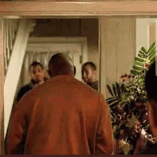 Man in Red Shirt Walking Through Doorway With Group