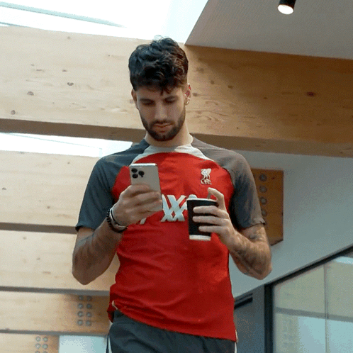 Man In Red Shirt With X Looking At Phone GIF
