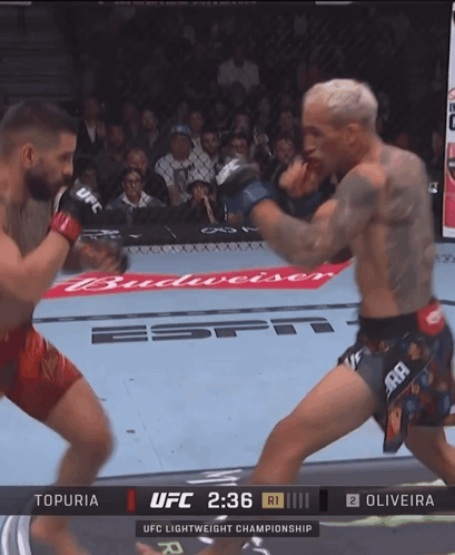 Man In Red Shorts Beside Man Lying In Cage GIF