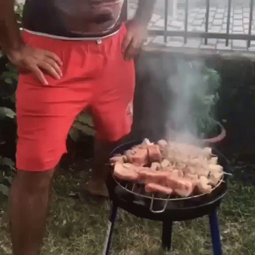 Man in Red Shorts Grilling Meat