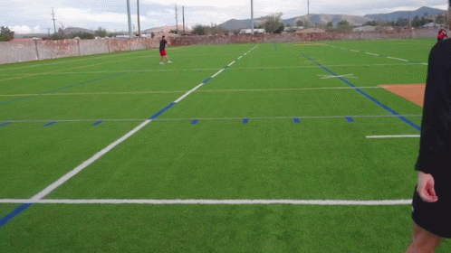 Man in Red Shorts on Soccer Field with Mountains