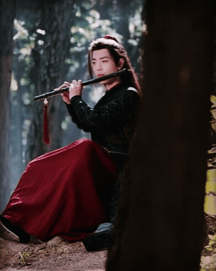 Man in Red Skirt Playing Flute in Forest