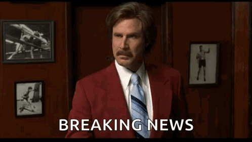 Man in Red Suit and Tie Holding Breaking News