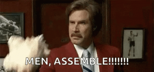 Man in Red Suit and Tie Holding Stuffed Animal Saying Men Assemble