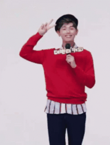 Man in Red Sweater Holding Microphone and Peace Sign