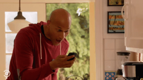 Man in Red Sweatshirt Looking at Cell Phone