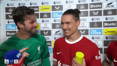 Man in Red Talking to Man in Green Holding Yellow
