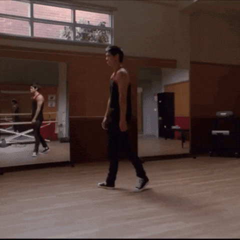 Man in Red Tank Top Walking on Wooden Floor