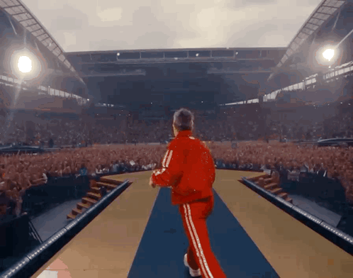 Man in Red Tracksuit Walking into Crowded Stadium