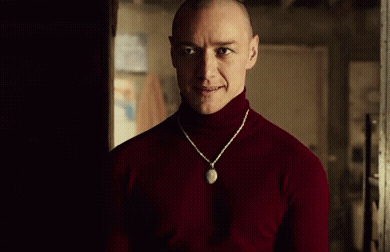 Man in Red Turtleneck and Necklace in Dark Room