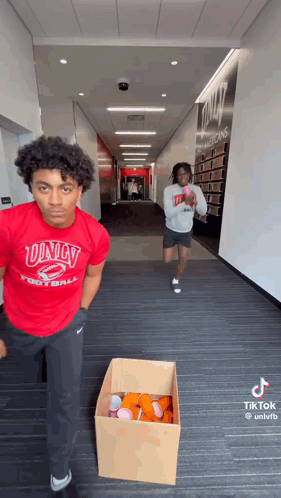 Man in Red Univ Football Shirt Next to Beer Cups Box