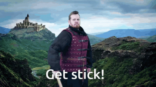 Man in Red Vest by Mountain Saying Get Stick