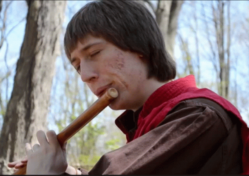 Man in Red Vest Playing Flute in Woods