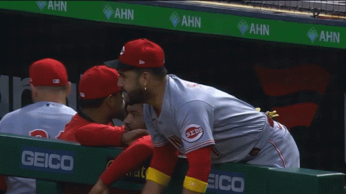 Man in Reds Jersey Hugging Another in Dugout