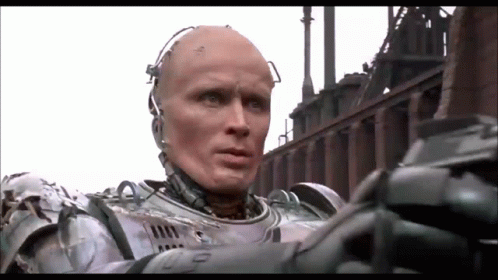 Man in Robot Suit in Front of Factory