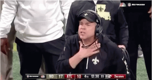 Man in Saints Hat and Headphones on Football Field