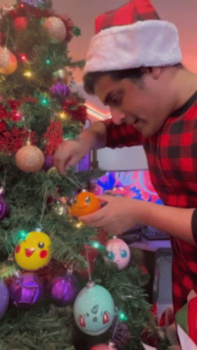 Man In Santa Hat Decorates Christmas Tree GIF