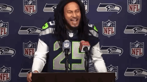 Man in Seahawks Jersey at Podium in Front of NFL Logo