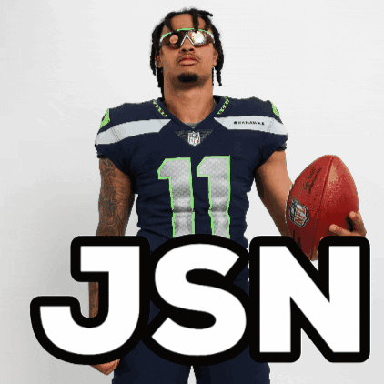 Man In Seahawks Jersey Holding Football In Front Of JSON Sign GIF