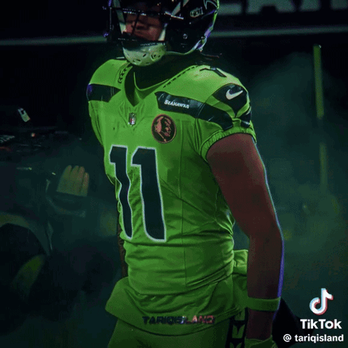 Man in Seahawks Uniform Smiling in Front of Scoreboard Saying 1:49