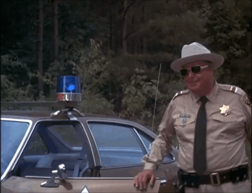 Man In Sheriff Uniform Leaning On Car GIF