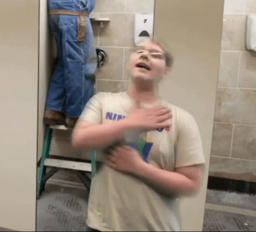 Man In Shirt Saying Nin Standing In Bathroom GIF