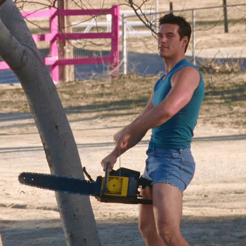 Man In Shorts Holding Chainsaw GIF