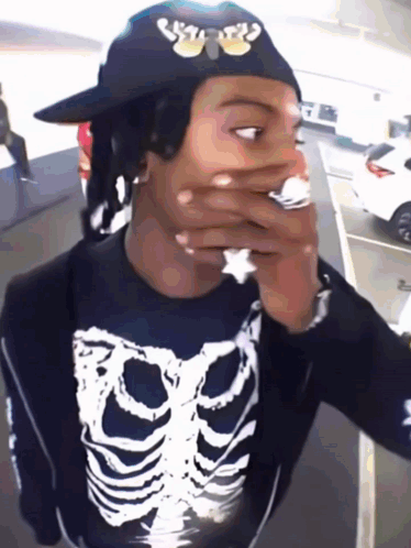 Man in Skeleton Shirt With Hat Over Mouth