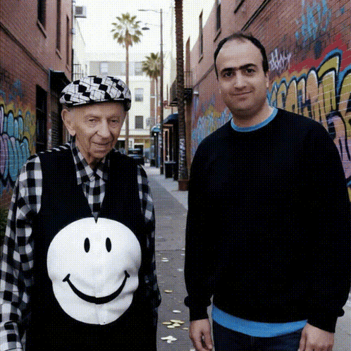 Man in Smiley Face Vest Beside Older Man