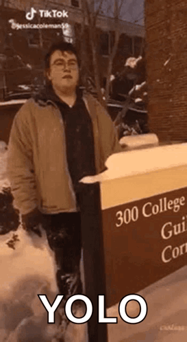 Man in Snow Next to YOLO Sign