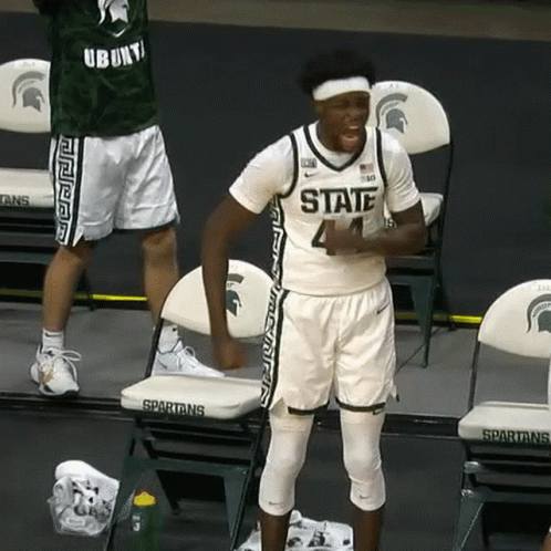 Man in Spartans Jersey Standing Before Chairs