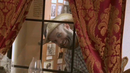 Man in Straw Hat Looking Out Window