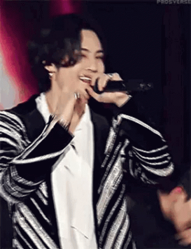 Man in Striped Jacket Singing Into Microphone