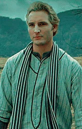 Man in Striped Shirt and Scarf Standing in Front of Mountain