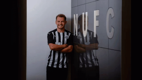 Man in Striped Shirt in Front of NFC Wall